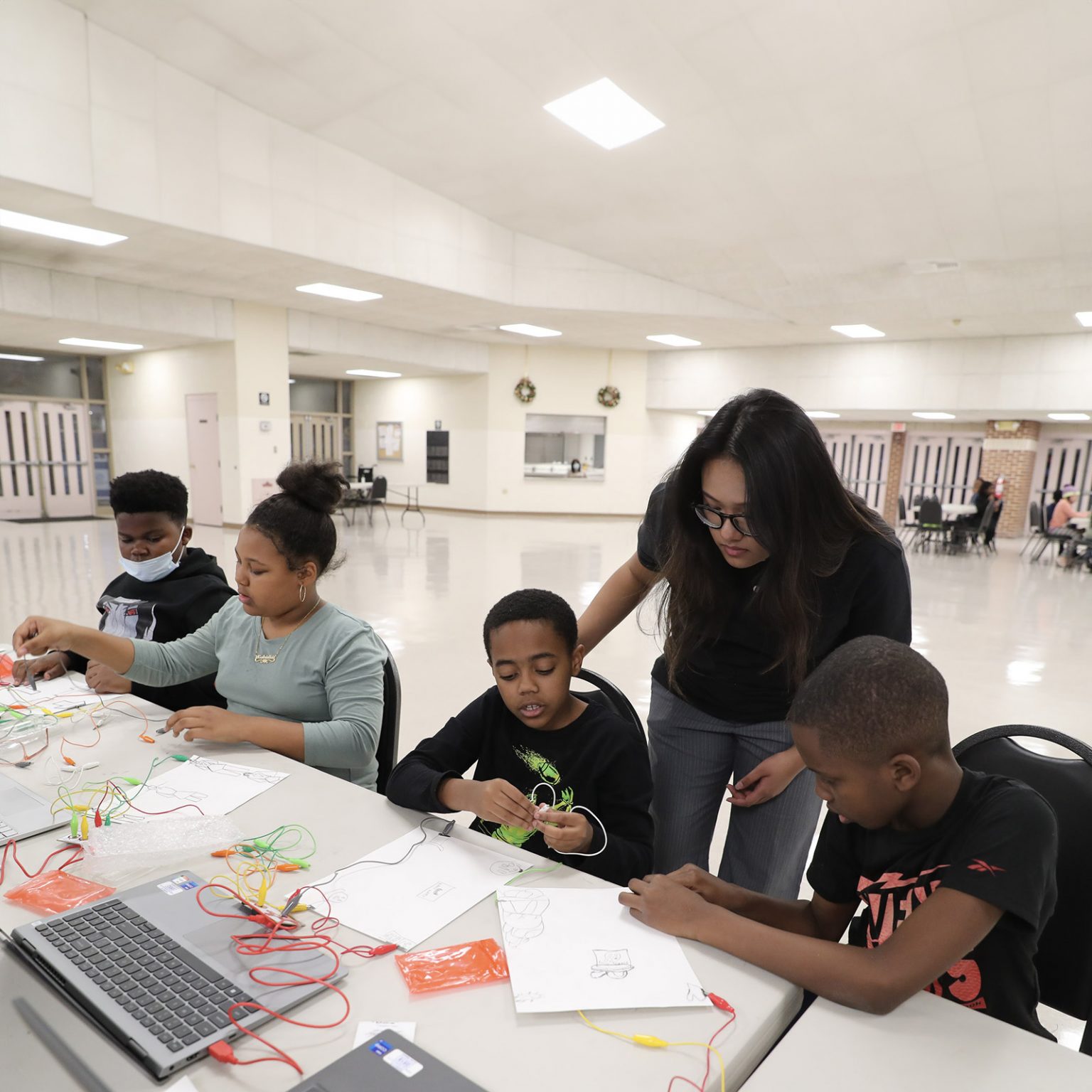 four students and an intern use electronic probes connected to laptops and paper